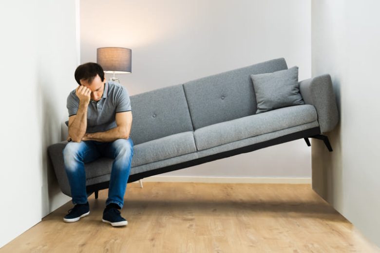 Man moving couch that doesn't fit